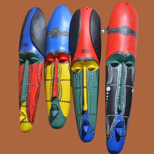 Four vibrant handcrafted African masks from Tanzania, featuring bold geometric patterns and vivid colors in red, blue, green, yellow, and black, each symbolizing tradition, creativity, and community spirit.